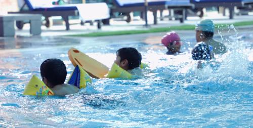 a group of children playing in a swimming pool at The Residency Hotel in Lahore