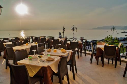 a restaurant with tables and chairs next to the water at Hotel Miralago in Lazise