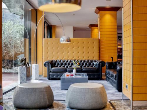 eine Lobby mit einem Sofa und zwei Hockern in der Unterkunft Sansi Pedralbes in Barcelona