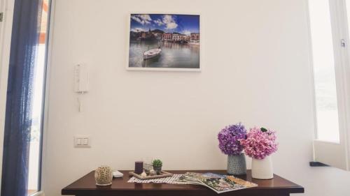 einen Tisch mit Blumen und ein Bild an der Wand in der Unterkunft Le 7 sorelle in Lipari