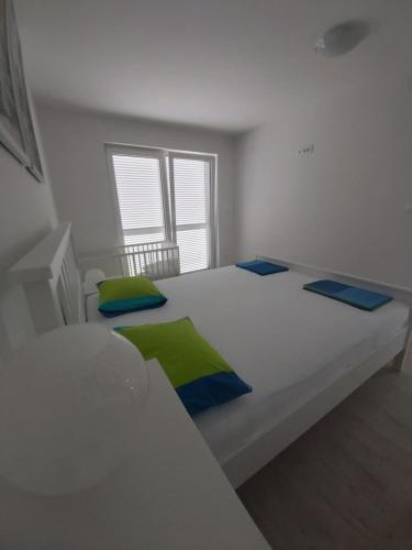 a white bed with blue and green pillows on it at Apartments Irina in Ičići