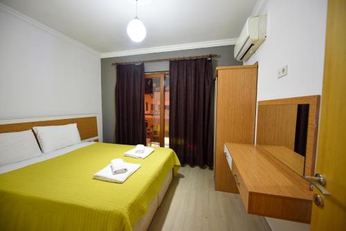 a room with a yellow bed with two towels on it at Lidya City Hotel in Fethiye