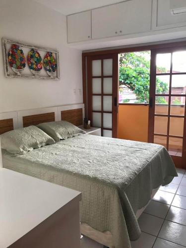 a bedroom with a large bed and two windows at Paz & Diversão Praia Do Forte in Praia do Forte