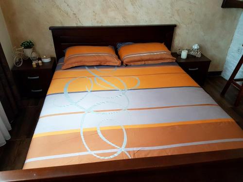 a bed with an orange and white comforter and pillows at Apartmani vuk in Cetinje