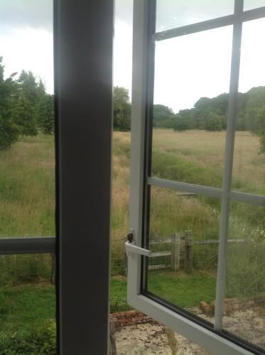 an open window with a view of a field at The Mill House in Berwick Saint James