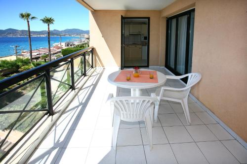 balcone con tavolo, sedie e vista sull'oceano di Residhotel Villa Maupassant a Cannes