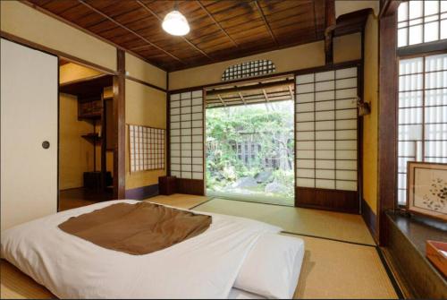 een slaapkamer met een bed in een kamer met een raam bij Guest House Koiya in Kyoto