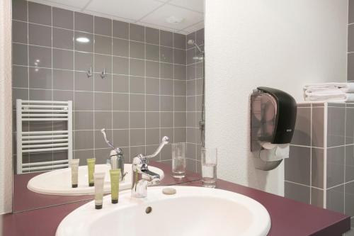 La salle de bains est pourvue d'un lavabo et d'un miroir. dans l'établissement Zenao Appart'hôtels Troyes, à Troyes