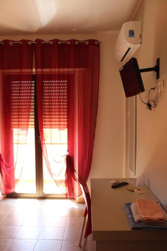 a room with a desk and a window with red curtains at B&b Paolo e Daniela in Carbonia