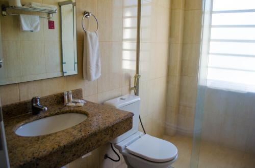 a bathroom with a sink and a toilet and a shower at Grande Hotel Glória in Águas de Lindóia
