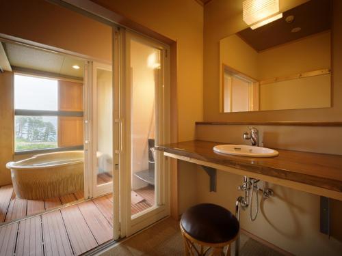 a bathroom with a tub and a sink and a bath tub at Nagisatei Taroan in Miyako