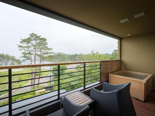 a balcony with two chairs and a large window at Nagisatei Taroan in Miyako