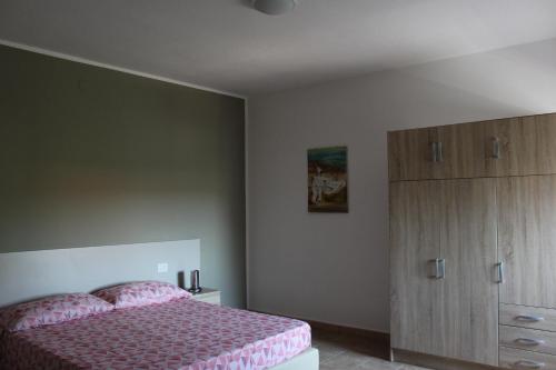 a bedroom with a pink bed and a dresser at B&b Paolo e Daniela in Carbonia