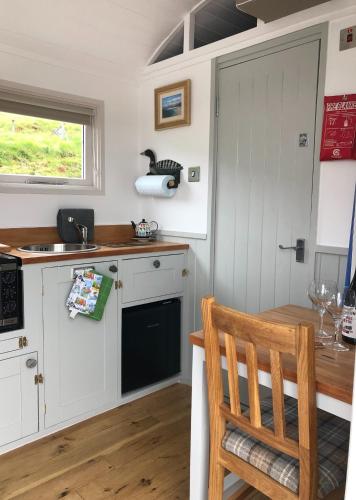 a kitchen with white cabinets and a wooden table at Fisherman's Hut in Tarbert