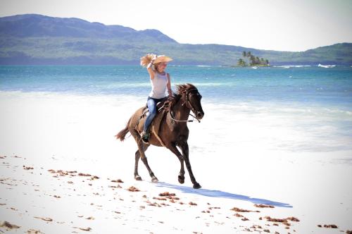 a person riding a horse on the beach at Hotel Villa Serena in Las Galeras