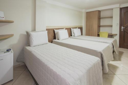 a hotel room with two beds with white sheets at Alfa Plaza Hotel in Brasília