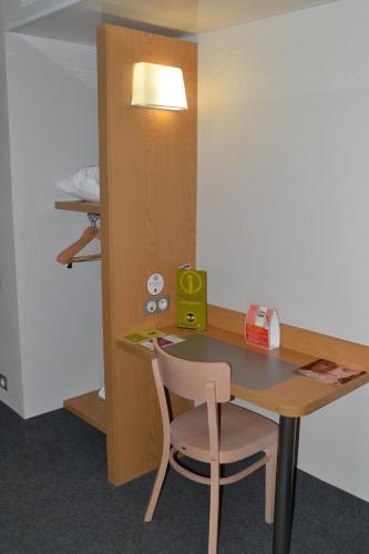 a desk with a chair and a table with a lamp at B&B HOTEL Grenoble Centre Alpexpo in Grenoble