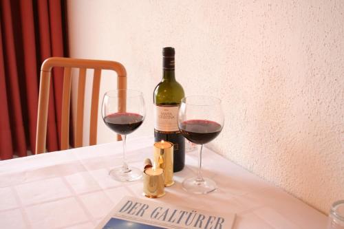 a bottle of wine and two glasses on a table at Hotel Garni Sport Sonneck in Galtür