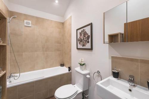a bathroom with a toilet and a tub and a sink at Beautiful West London House in London