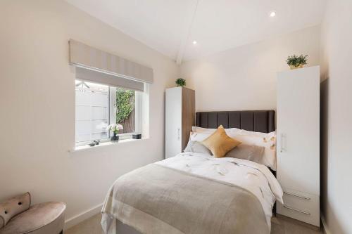 um quarto branco com uma cama e uma janela em Beautiful West London House em Londres