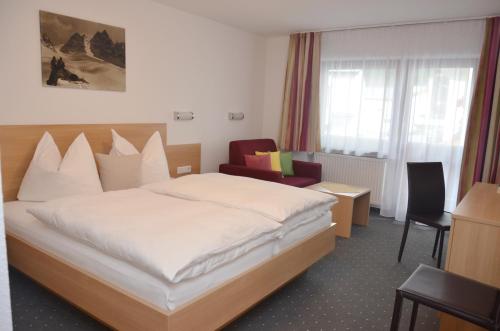 a hotel room with a bed and a chair at Hotel Garni Sport Sonneck in Galtür
