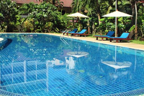 uma piscina com duas cadeiras e guarda-sóis em Patong Palace Hotel - SHA Extra Plus em Patong Beach