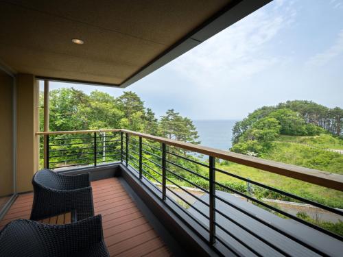 a balcony with two chairs and a view of the ocean at Nagisatei Taroan in Miyako