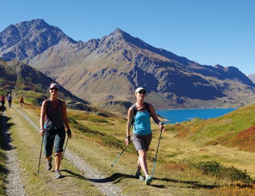 two women walking down a dirt road with poles at CIS-Ethic Etapes de Val Cenis in Lanslebourg-Mont-Cenis