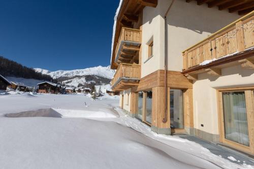 a building with snow on the ground in front of it at Chalet Cuna Bela in Livigno