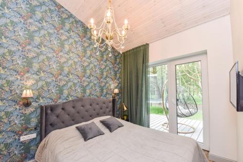 a bedroom with a large bed and a chandelier at Žalia kopa House in Palanga