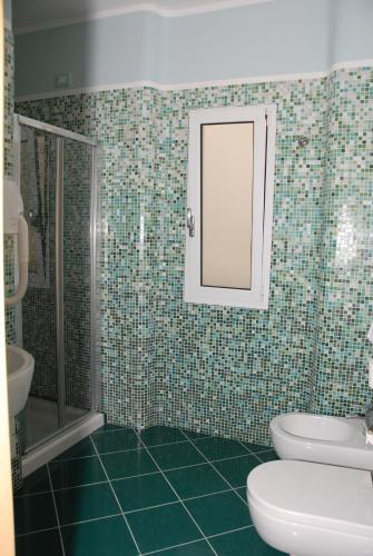 a bathroom with a toilet and a sink and a mirror at Hotel Miramare in Porto Cesareo