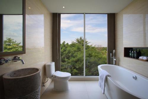 baño con bañera, aseo y ventana en The Crystal Luxury Bay Resort Nusa Dua, en Nusa Dua