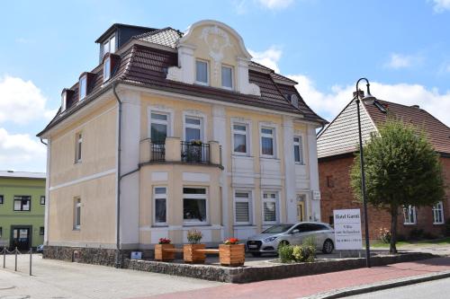 a white house with a car parked in front of it at Hotel Garni Villa am Schaalsee in Zarrentin