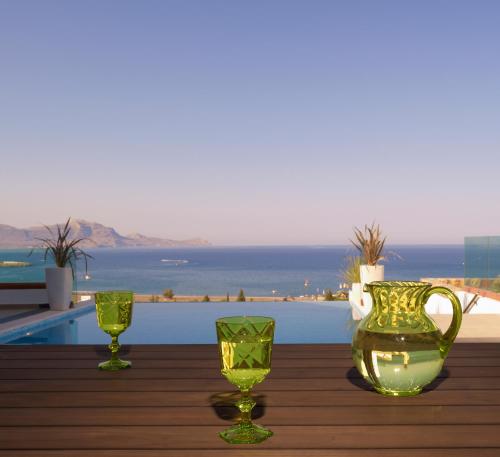 two green glasses and a vase on a wooden table at Luxury Villa Eos in vlicha