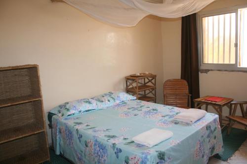 a bedroom with a bed with blue sheets and a window at Auberge Keur Diame in Dakar