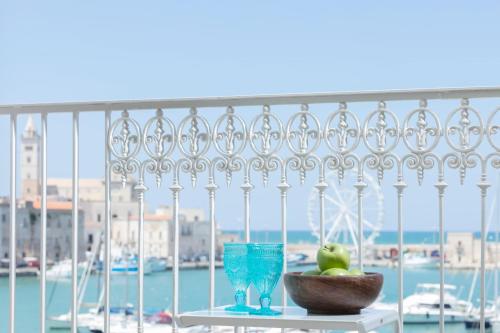 a table with a bowl of fruit and glasses on a balcony at Dimore Marinare in Trani