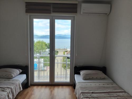 dwa łóżka w pokoju z dużym oknem w obiekcie Sunrise Hotel & Camping w mieście Struga