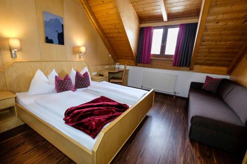 ein Schlafzimmer mit einem großen Bett und einem Sofa in der Unterkunft Aktiv Hotel Karnia in Hermagor
