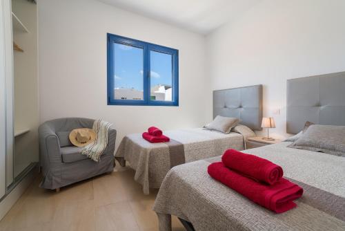 - une chambre avec deux lits, une chaise et une fenêtre dans l'établissement CALIMAS, à Caleta de Sebo
