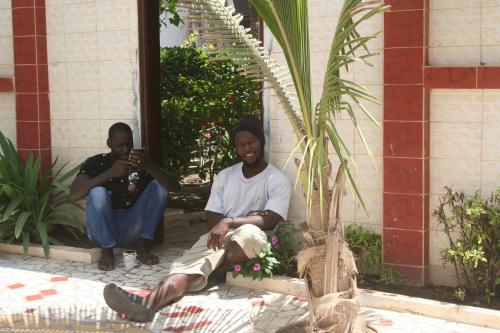 two men sitting on the ground next to a palm tree at Auberge Keur Diame in Dakar
