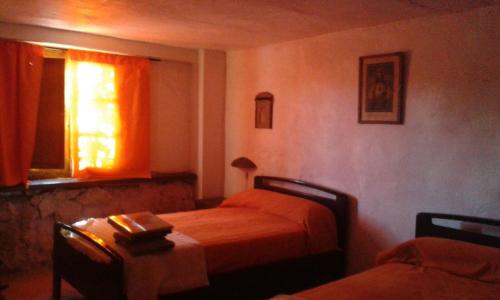 a bedroom with two beds and a table and a window at Alojamiento Rural Luís y María in Villanueva de Algaidas
