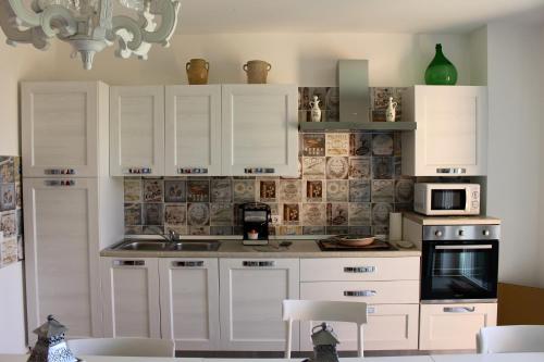 een keuken met witte kasten, een wastafel en een magnetron bij B&B Tra Cielo e Mare in Soverato Superiore