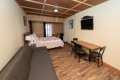 Habitación con cama, mesa y sillas. en Auberge Le Four à Pain en Petite-Rivière-Saint-François