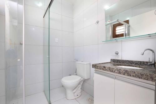 a white bathroom with a toilet and a sink at Porto Seguro Flat in Pecém