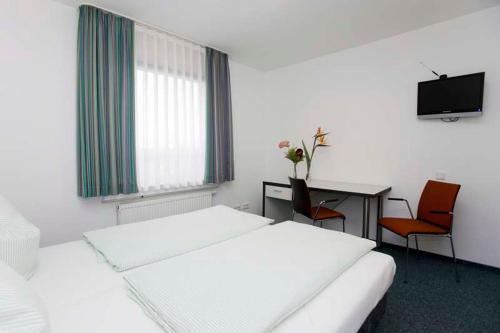 a bedroom with a bed and a desk and a tv at Jugendherberge Köln-Deutz in Cologne