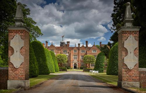an entrance to a house with hedges and a driveway at Great Fosters - Near Windsor in Egham