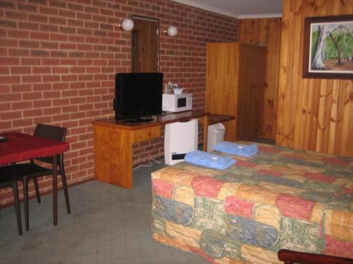 a room with a bed and a microwave and a table at Orbost Country Road Motor Inn in Orbost