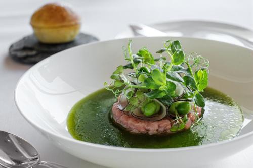 a white bowl with a piece of meat with greens on it at Hotel Eden Roc - The Leading Hotels of the World in Ascona