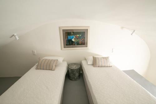 two beds in a room with white walls at Aloia Villas in Oia