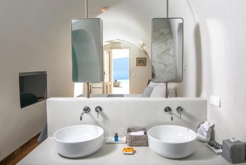 a bathroom with two white sinks and a mirror at Aloia Villas in Oia